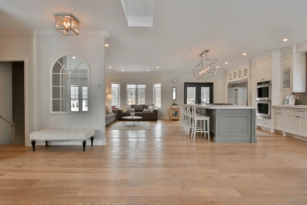 Open-concept living room and kitchen showcasing light wood-plank flooring